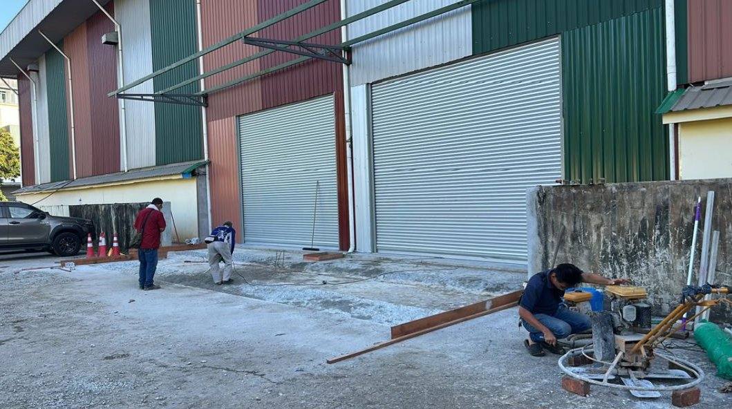 Workers carrying out concrete floor works outside roller shutters at CK Sport Centre